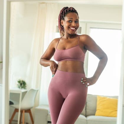 Woman in activewear smiling in a mirror at home