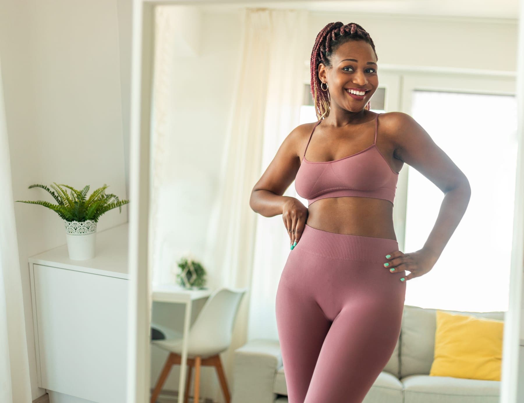 Woman in activewear smiling at her reflection at home