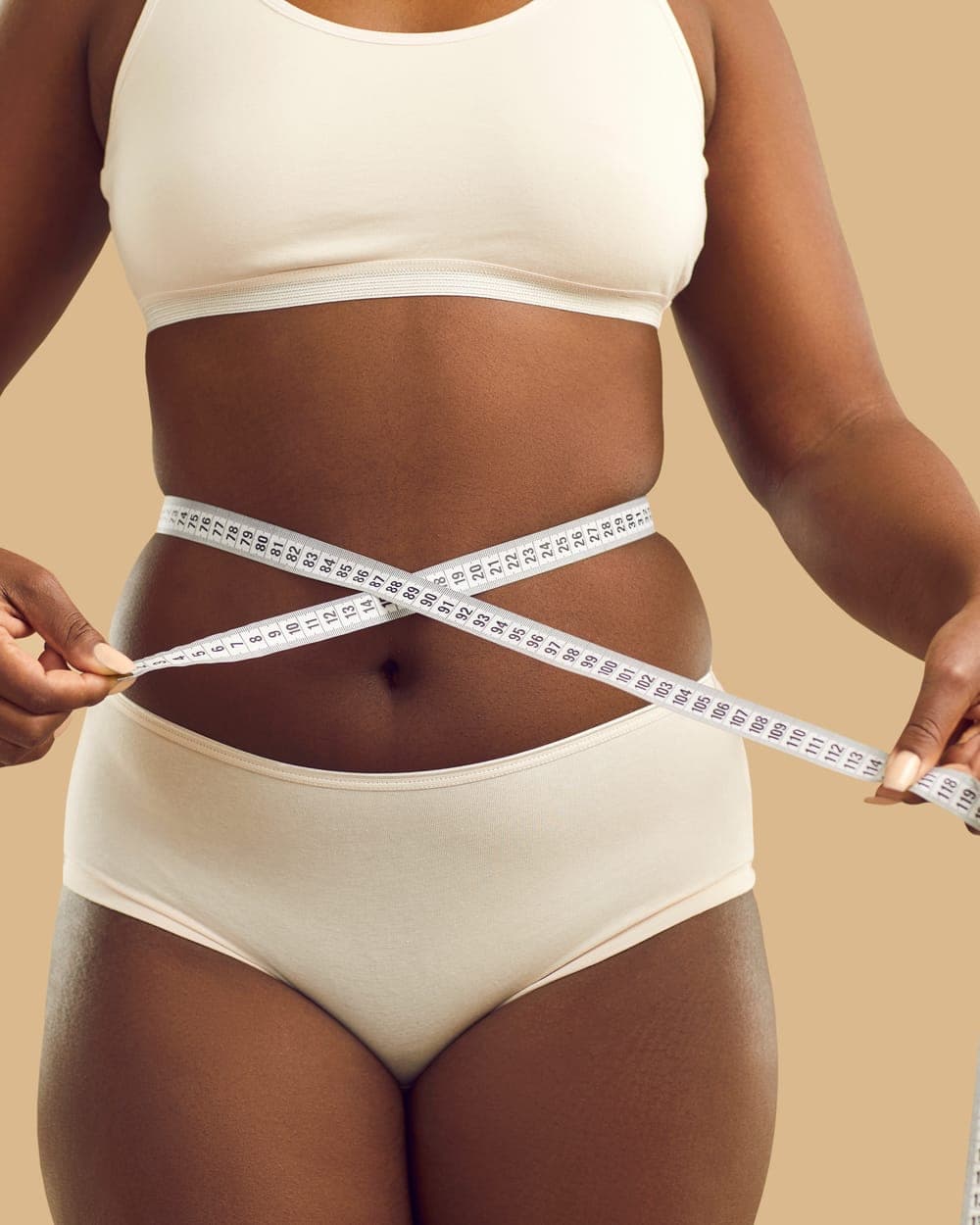 Woman measuring her waist with a tape measure