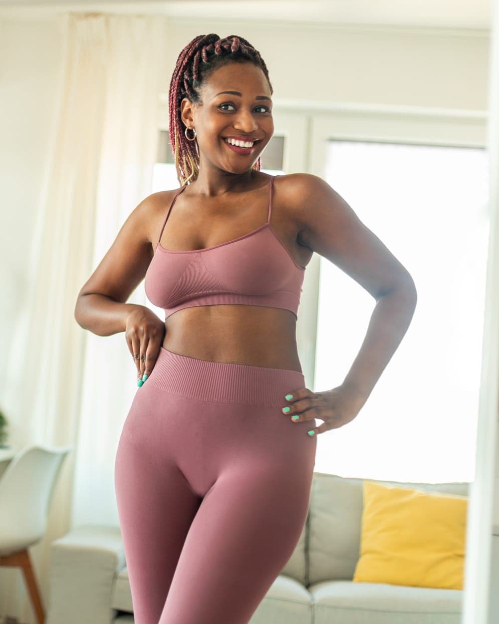 Woman in activewear smiling in a mirror at home
