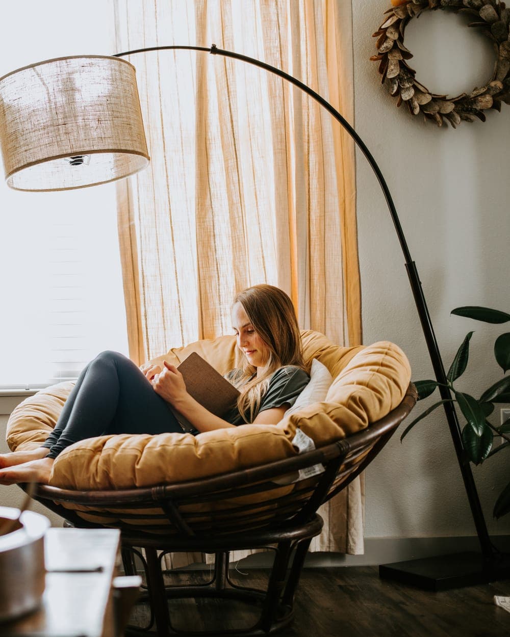 Young woman reading in a chair by the window at home